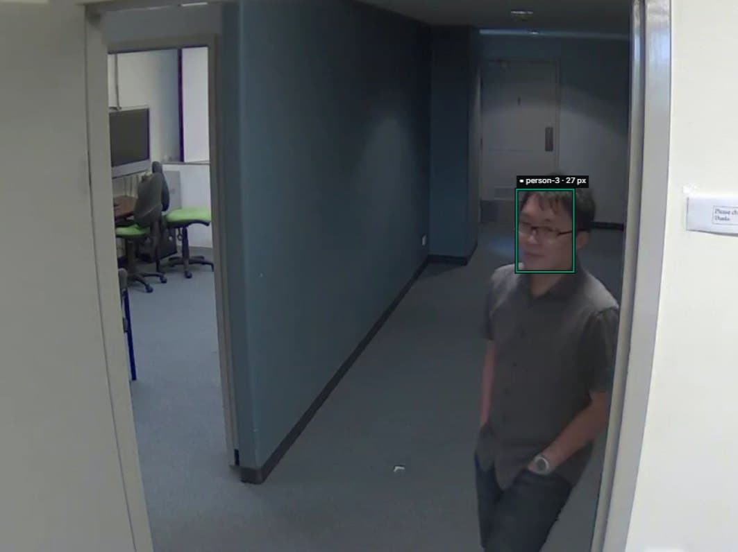 Corridor CCTV frame with a person walking toward the camera